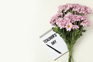 Flowers and notebook with words TEACHER'S DAY on white background, flat lay. Space for text