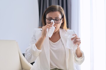 Woman sneezes in handkerchief, businesswoman got sick in the office