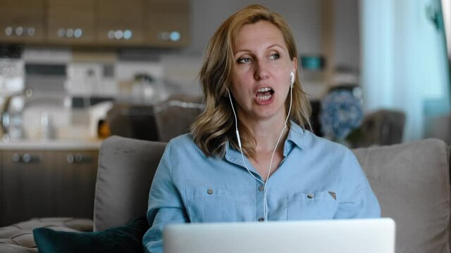 tutor teacher talking with client on online video call Rbbro. woman explain, consult with gesture. middle age female sit on couch on kitchen and use laptop. concept greet, smile
