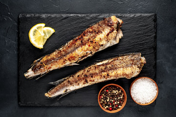 fried hake fish with spices on a stone background
