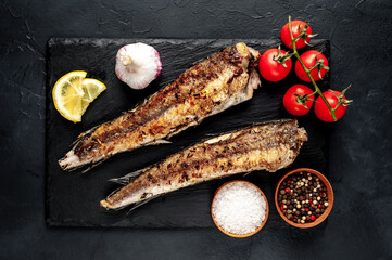 fried hake fish with spices on a stone background