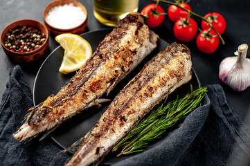 fried hake fish with spices on a stone background