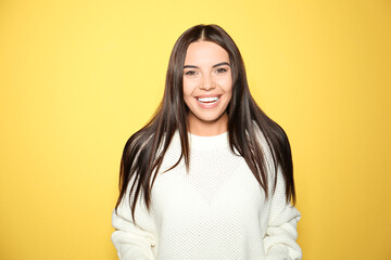 Happy young woman wearing warm sweater on yellow background