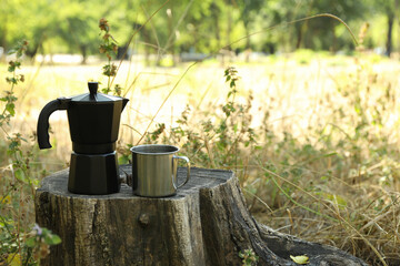 Coffee maker and metal cup on stump outdoor