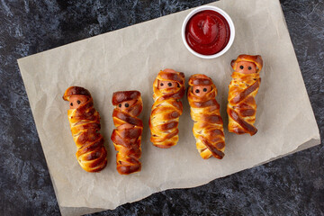 Scary sausage mummies in dough for kids party. Funny crazy Halloween food for children.