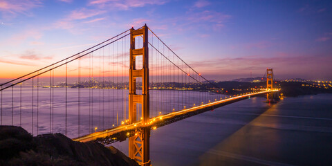 Traffic across the Golden Gate Bridge in San Francisco forms light trails as dawn rises behind
