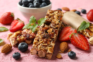 Granola bars and bowl with blueberry on pink background, closeup