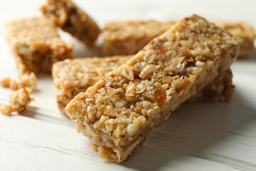 Tasty granola bars on white wooden background