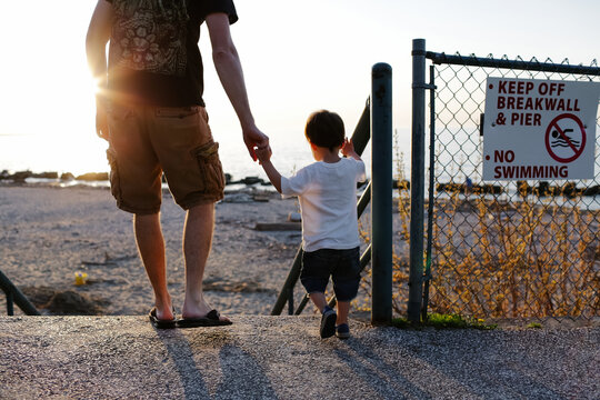 father and son walk to beach holding hands