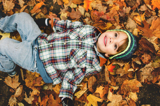 boy lays in leaves in fall