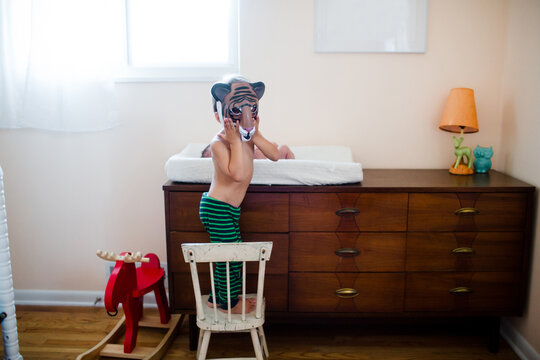 photo of brother with tiger mask and baby on changing pad on dresser