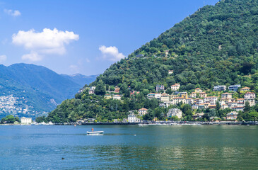 Fototapeta na wymiar Man on small boat on Lake Como with towns and mountains in the background