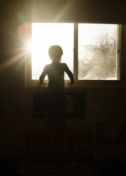 Child Stands In Sunny Window