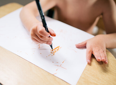 toddler writes at desk with marker
