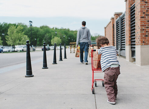 little boy pushes small shopping cart