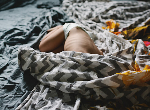 skinny child hides under blanket