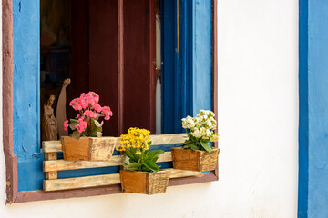 Fototapeta na wymiar Window decorated with flowers and objects in the historic city of Tiradentes typical of the interior of the state of Minas Gerais