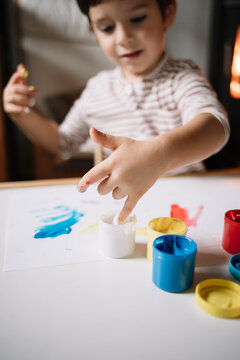 Young boy painting with his hands with tempera