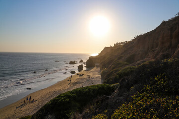 people playing on the beach at sunset with deep blue ocean water and waves rolling in  at El...