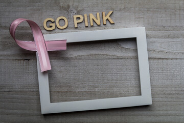 Pink Ribbon white frame GO PINK on weathered gray board for cancer awareness, women's health, breast cancer.  Copy space.