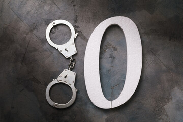 Handcuffs and number zero on the table, top view. Concept on the topic of zeroing prison terms