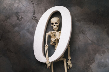 Human skeleton and number zero on a dark background, top view. Zeroing concept