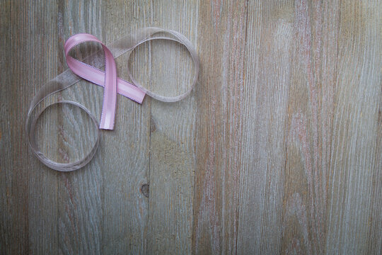 Pink Ribbon on weathered gray board for cancer awareness, women's health, breast cancer.  Copy space.