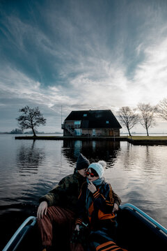 beautiful mature couple having fun sitting on a original boat on the lake in a winter day