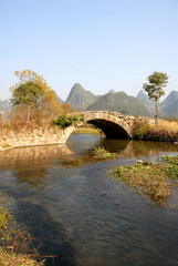 Scenery along the Yulong River near Yangshuo, Guilin in Guangxi Province, China. An ancient stone bridge near Yangshuo. The old bridge crosses a stream connecting farmland near to the Yulong River.