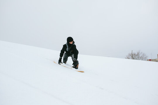 child snowboarding down hill