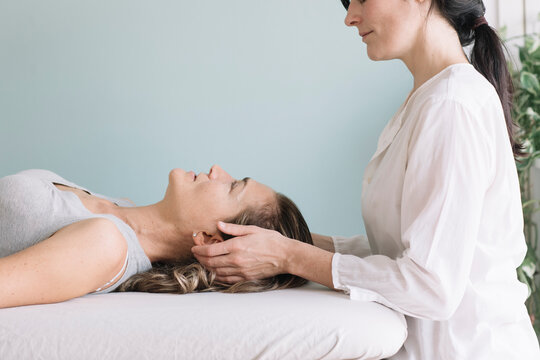 Professional Osteopath Working With Relaxed Caucasian Woman