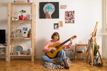 Young woman playing guitar at home