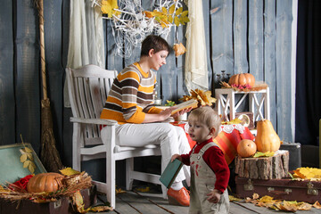 mom reads a book on a chair, daughter walks with a book in halloween decorations