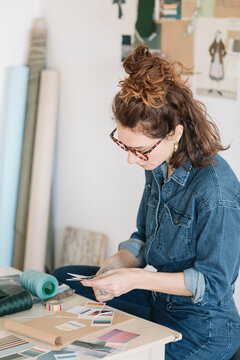 Young Woman Cutting Pantone Colours For Moodboard