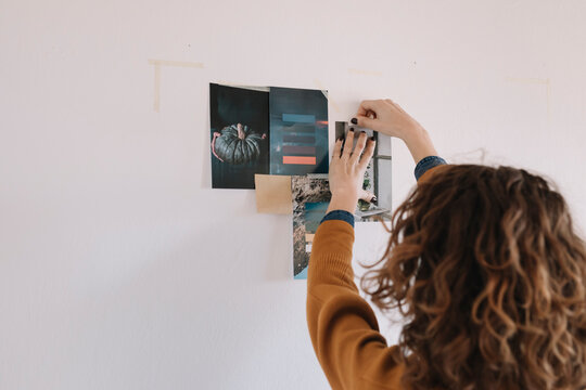Anonymous Young Woman Selecting And Hanging Pictures For Moodboard