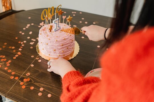 mom cutting into cake for one year old