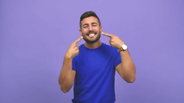 Young caucasian handsome man smiles, pointing mouth, concept of perfect teeth, white teeth, has a cheerful and jovial attitude