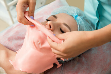 Young beautiful woman get alginate modeling mask to the face in a beauty salon.