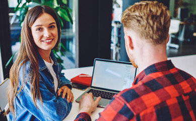 Fototapeta premium Portrait of cheerful Caucasian student smiling at camera during private lesson with male user for e learning software developing, collaborative meeting of young freelancers for doing distance job