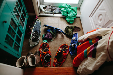 pile of boots and snowshoes by front door of home