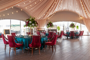 The summer tent is decorated with flowers and textiles on the wedding day