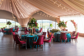 The summer tent is decorated with flowers and textiles on the wedding day