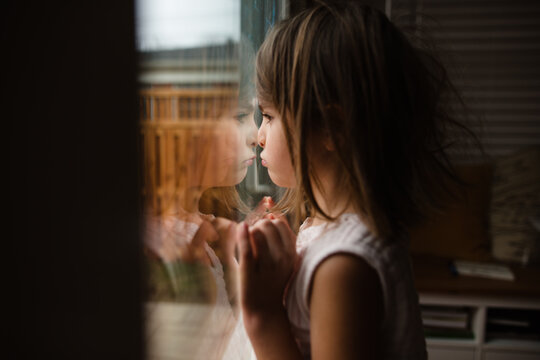 little girl makes faces by window