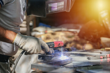 worker welds metal with electric welding