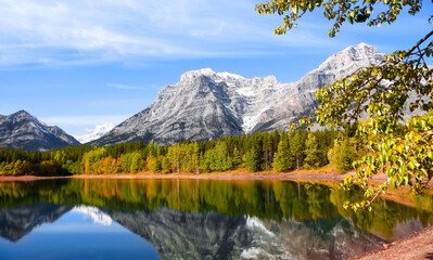 Fototapeta na wymiar Aspen and Maple trees in early autumn time by Wedge pond with tree and mountain reflections 