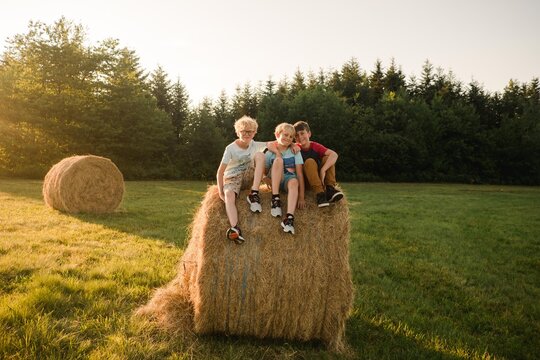 three boys being silly together on a hay bale