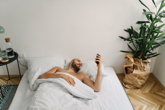 Young handsome man using his mobile phone in the bed