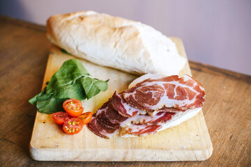Bondiola de cerdo en tabla con pan rúcula y lechuga para sandwich