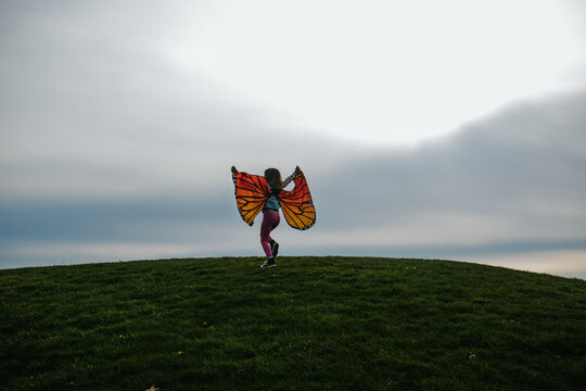 little girl running in field with butterfly wings