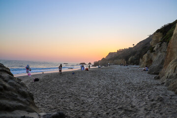 people playing on the beach near the ocean at sunset  at El Matador beach in Malibu California